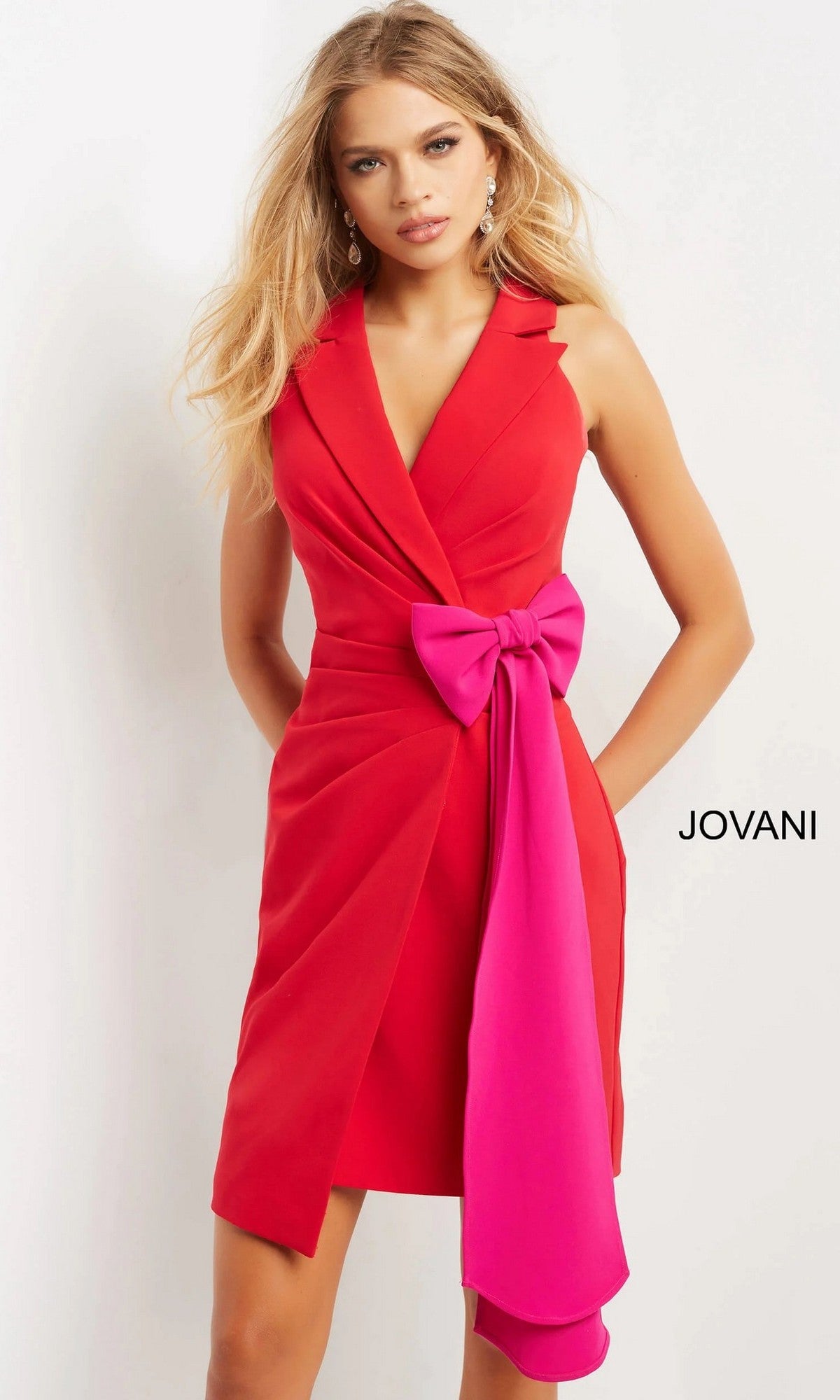 A woman models the Jovani 07961 short party dress, featuring a sleeveless red/fuschia design with a prominent pink bow at the waist, set against a plain white background.